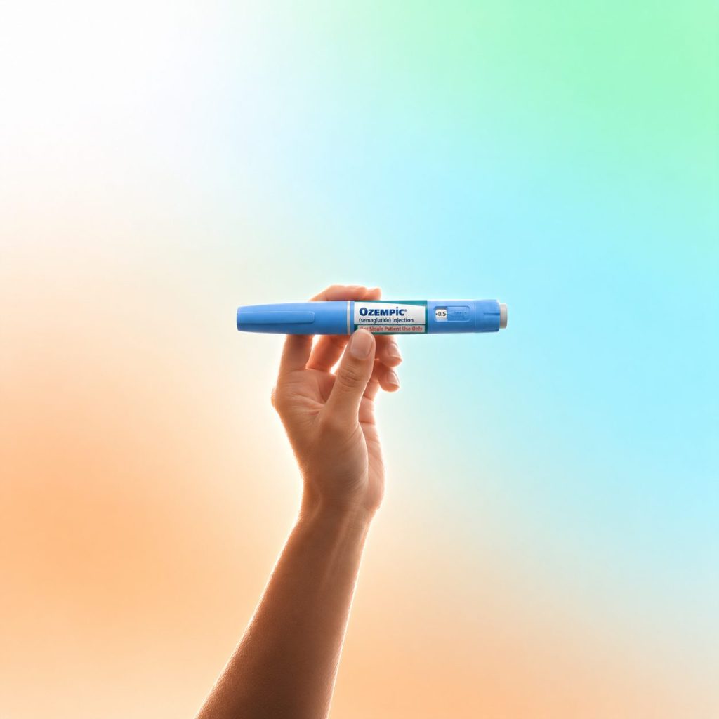 A hand holding a GLP-1 injection pen against a soft maple and sky glow
