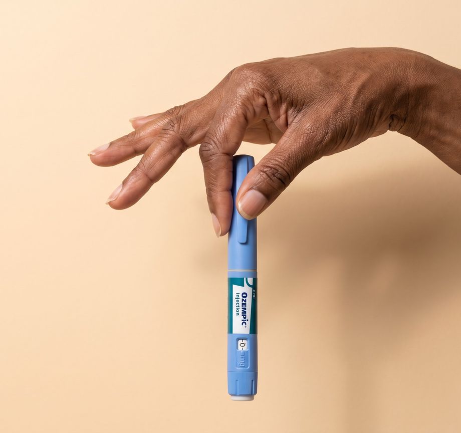 A hand holding a blue injector pen